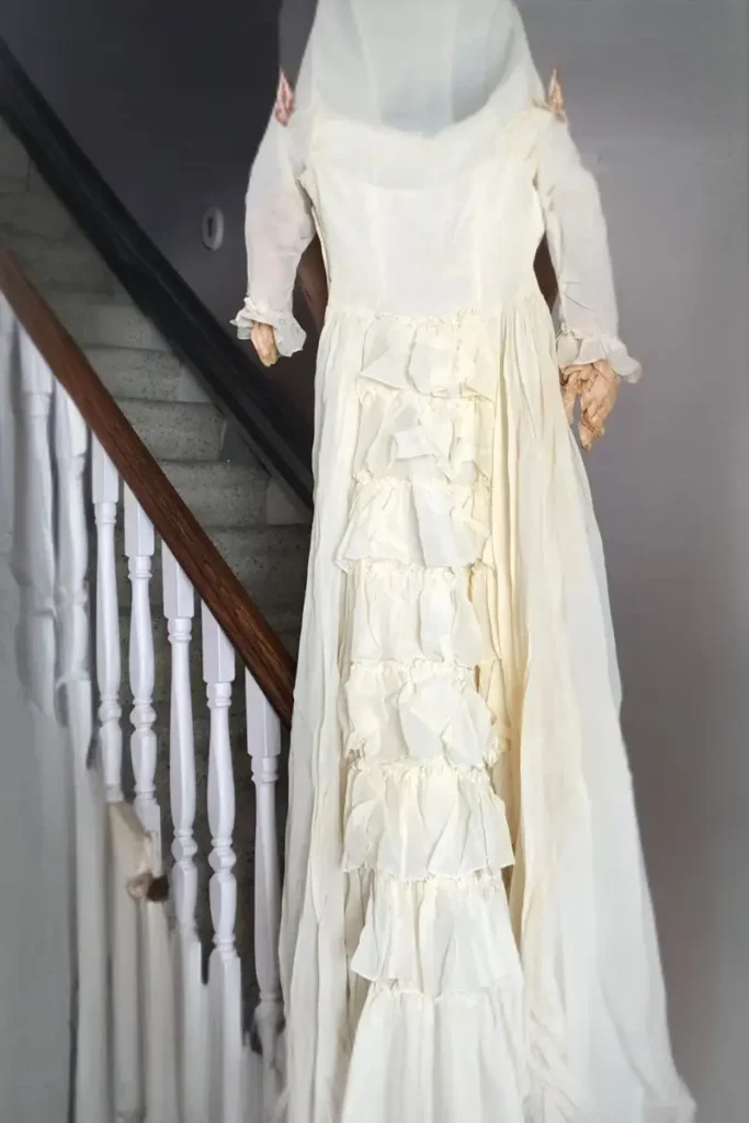 A 1945 ivory organza wedding dress with delicate tiered ruffles displayed on a staircase, a mother's cherished heirloom and a symbol of healing grief after losing your mother