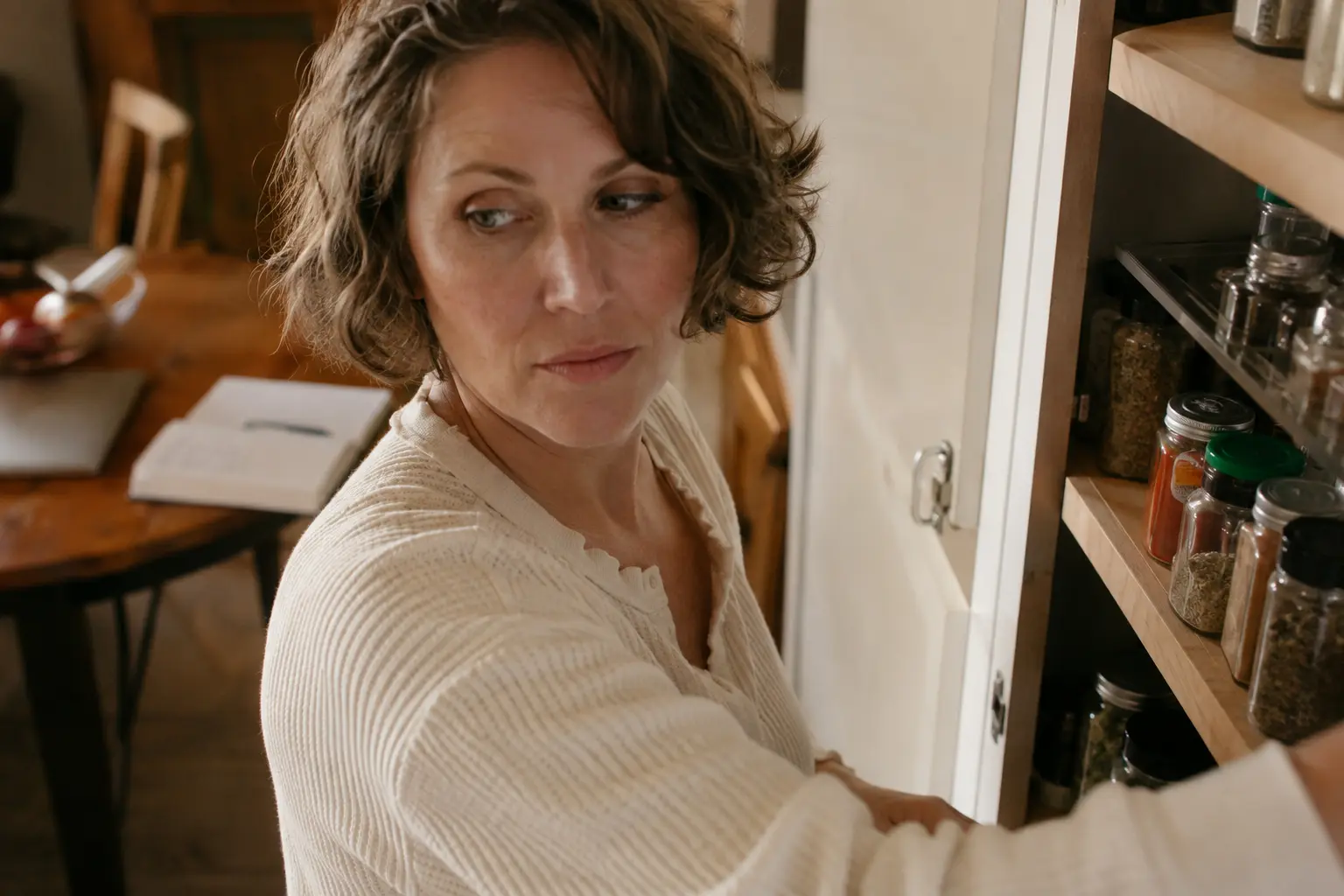 A woman reorganizing her pantry instead of finishing a task, an everyday example of why you keep getting in your own way.